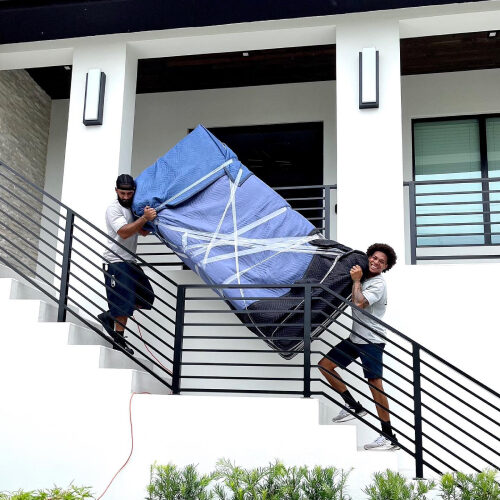 Moving Company Harbour Island Florida Two Employees of Harbour Island Moving Company Carrying a Heavy Furniture Down the Stairs