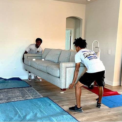 Moving Company Jacksonville Florida Two Employees of Jacksonville Moving Company Lifting Up a Sofa