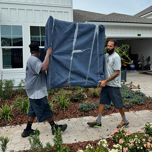 Two Moving Company Employees Lifting Heavy Furniture of a Lakeshore Ranch Family