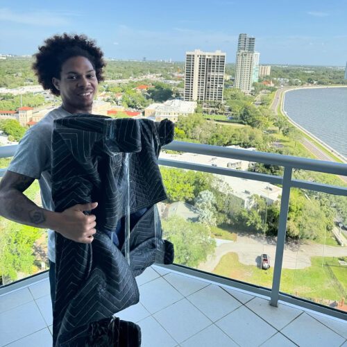 Moving Company Employee Holding Couch in the Balcony with South Tampa FL in the Background