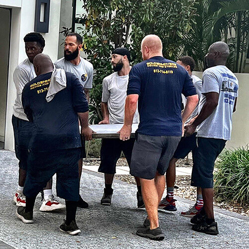 Employees of Brandon Florida Moving Company Carrying a Heavy Furniture Together