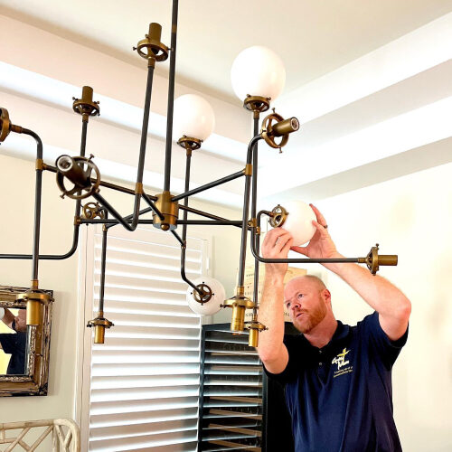 Owner of South Tampa Moving Company Removing Bulbs of a Chandelier