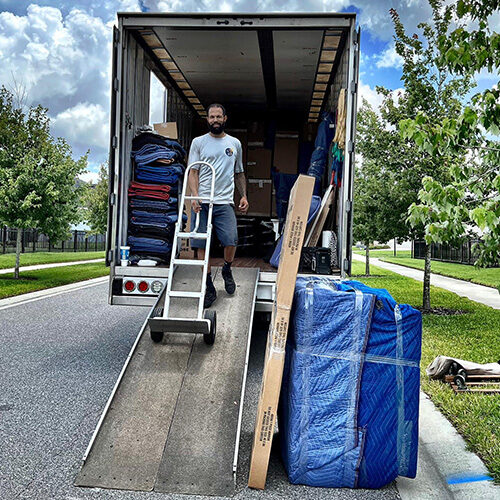 Employee of a Moving Company in Westchase FL Going Down the Truck While Pushing a Trolley