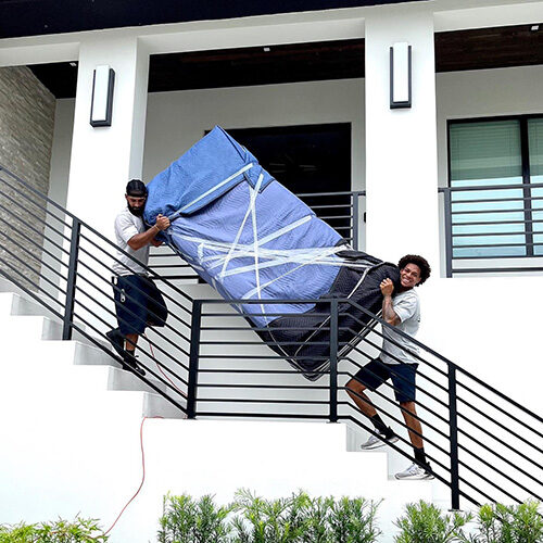 Moving Company in Miami Florida Moving Company Employees Carrying Sofa Up the Stairs of Building in Miami FL