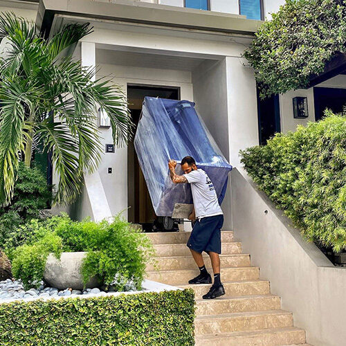 Residential Moving Company in Tampa FL Tampa Employee of Residential Moving Company Carrying Sofa Down The Stairs